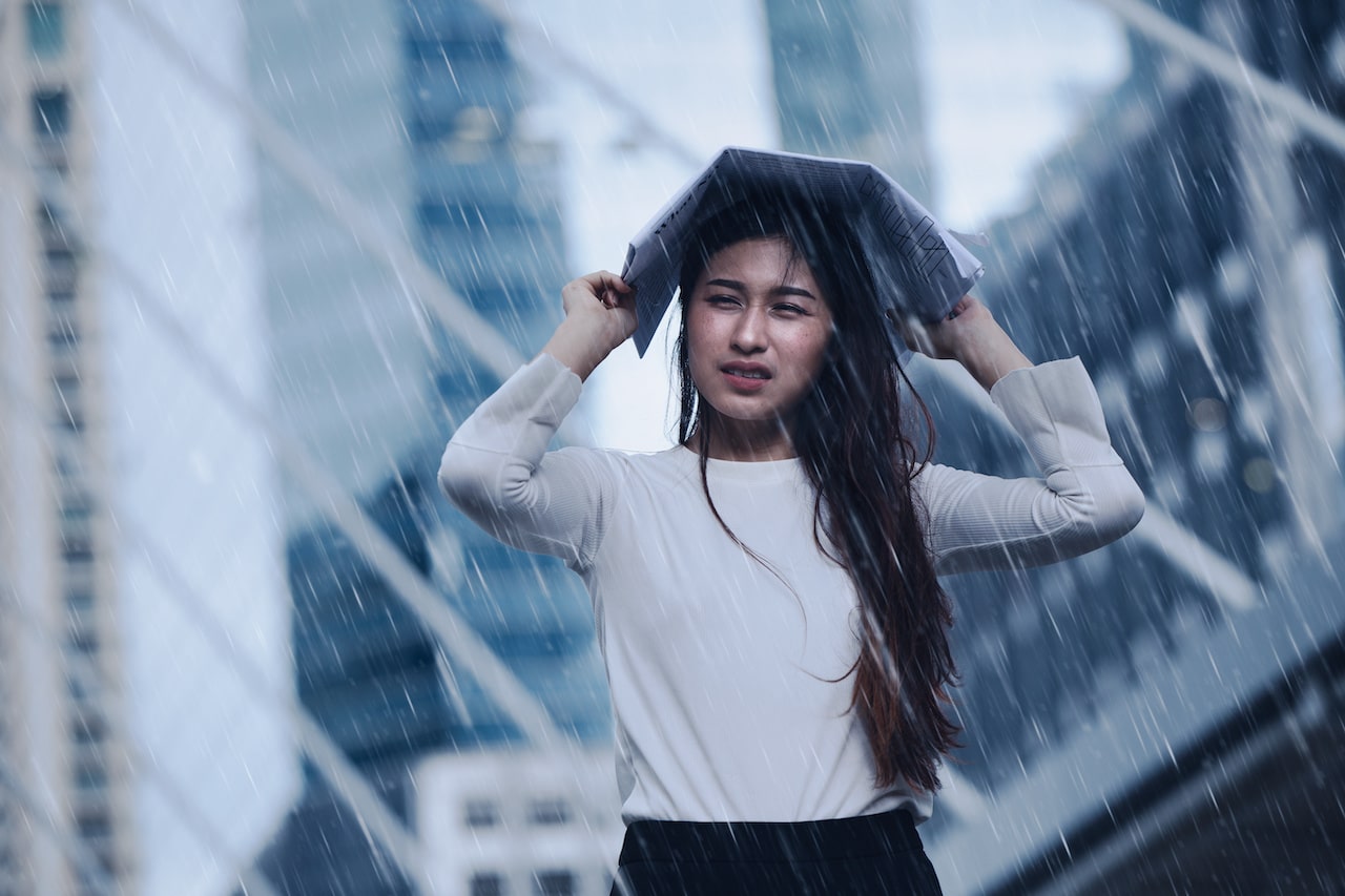 A woman in a white shirt standing in the middle of a city during a rainstorm, holding a book over her head to stay dry. Digital Amplification has a team of experienced marketing leaders to help clients prepare for economic storms. Unlike the woman in the photo who was left in the rain.