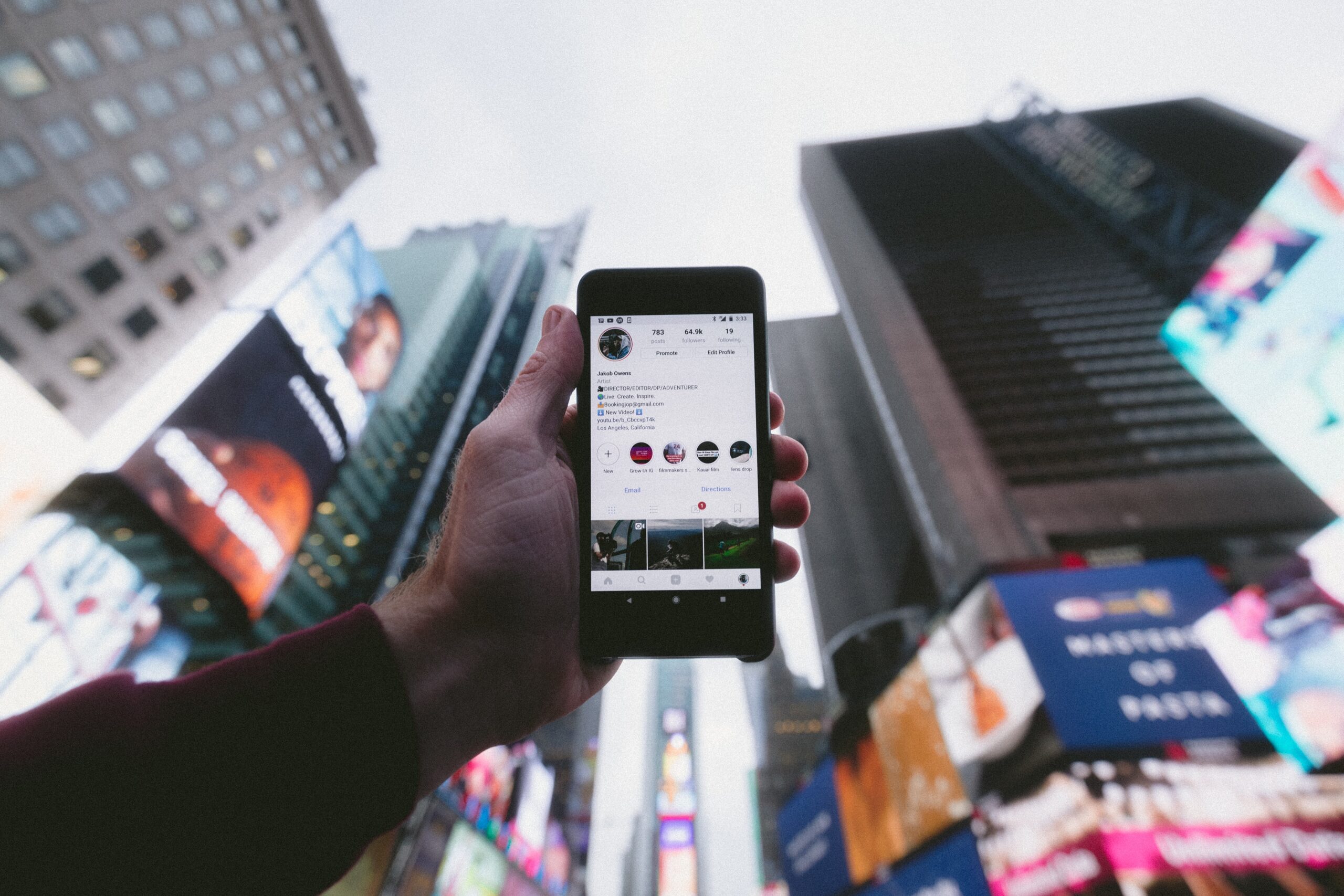 Person holding phone with social media displayed in a city center