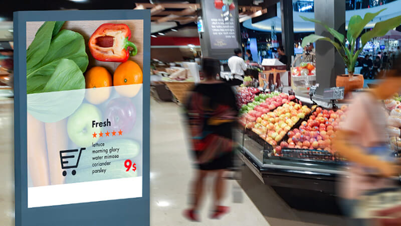 Shoppers in the produce section of a grocery store with an inset image of a smartphone showing how ads on store apps are helping shoppers navigate the store and find new brands and products to try.