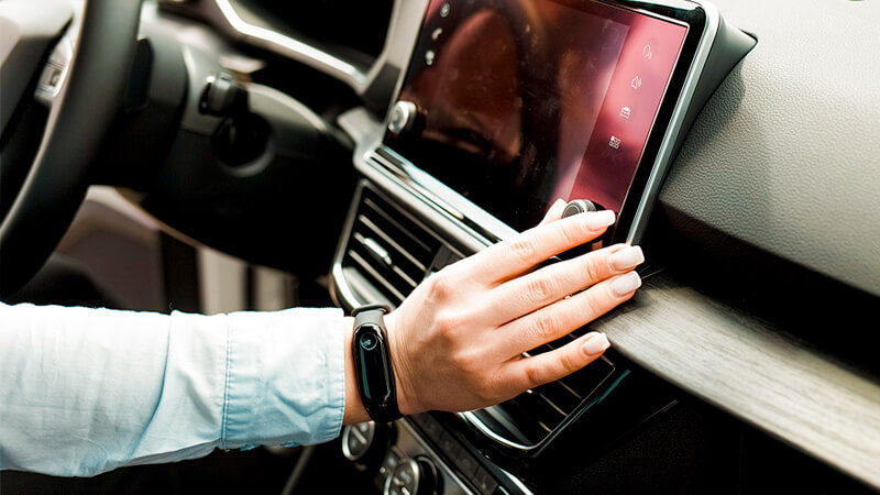 A profile photo of a woman driving a car with a smart radio device.  She is adjusting the channel to select her favorite streaming audio station.