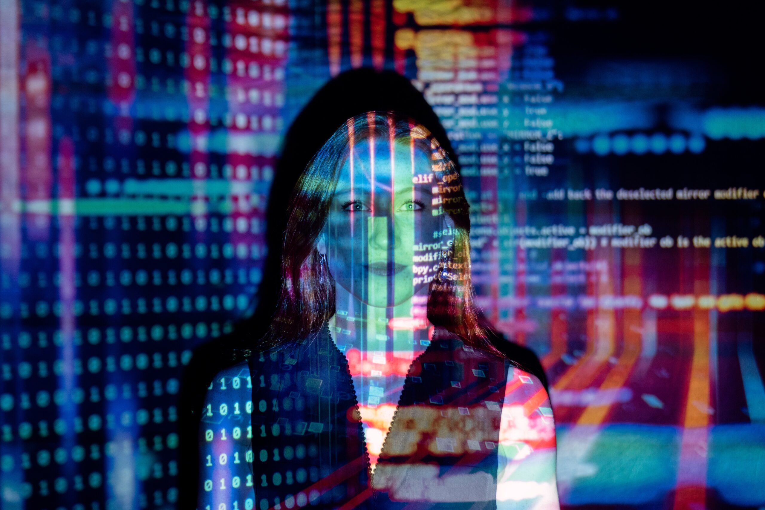 A brilliant marketing leader is processing information to optimize her marketing efforts. Woman standing against a black wall with digital data projecting towards her.