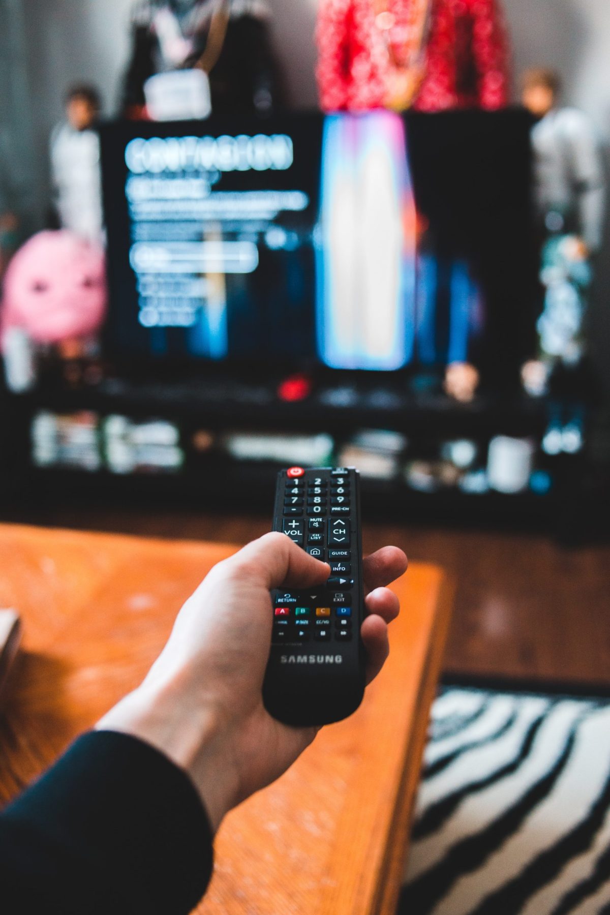 A hand holding a remote that is pointed at a TV.
