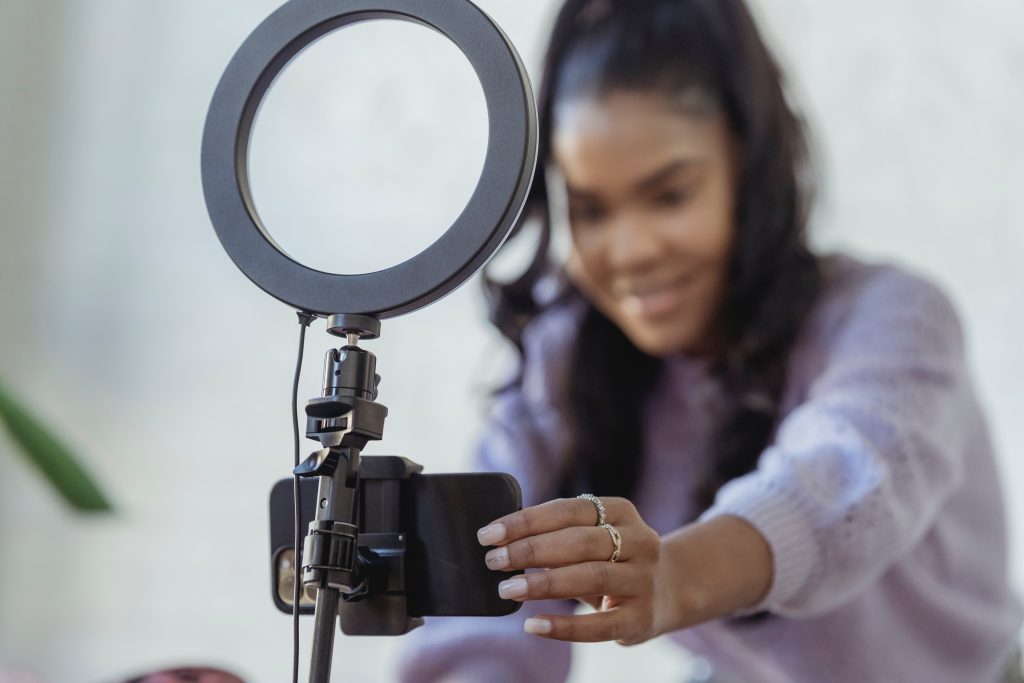 A woman setting up a phone and ring light preparing to post on social media 