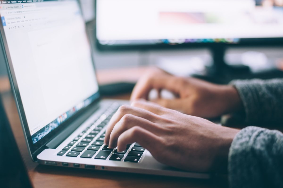 Hands typing on a laptop keyboard, searching for information online