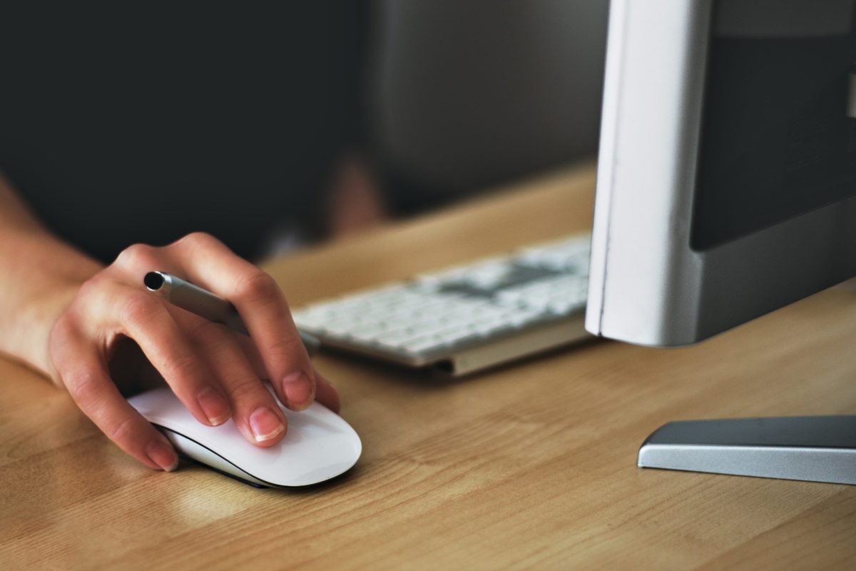 A hand holding a mouse, the mouse scroll wheel is being used to navigate the internet