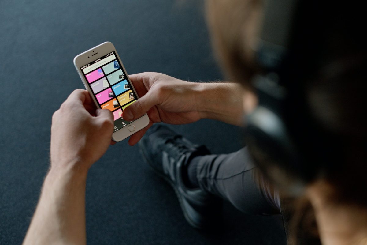 A man wearing headphones while scrolling through an audio streaming app