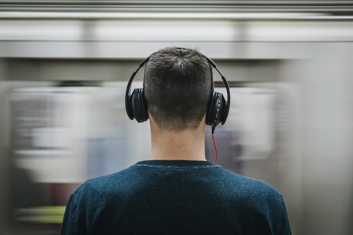 A man standing in the subway with a pair of headphones on