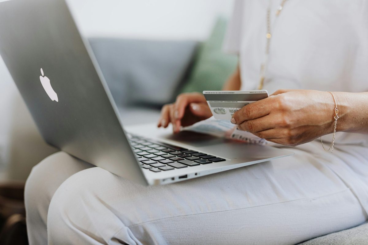 A person online shopping while holding a credit card