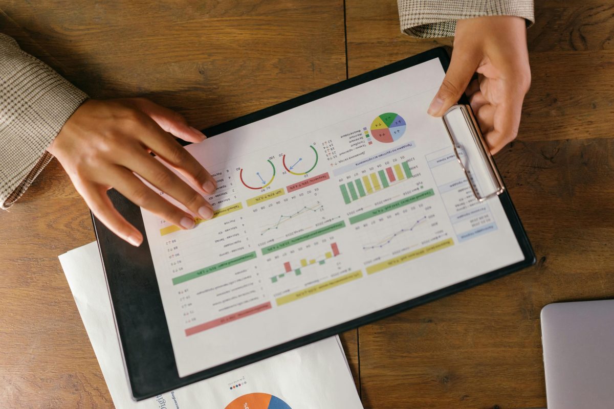 Hands holding a piece of paper that displays many charts and graphs