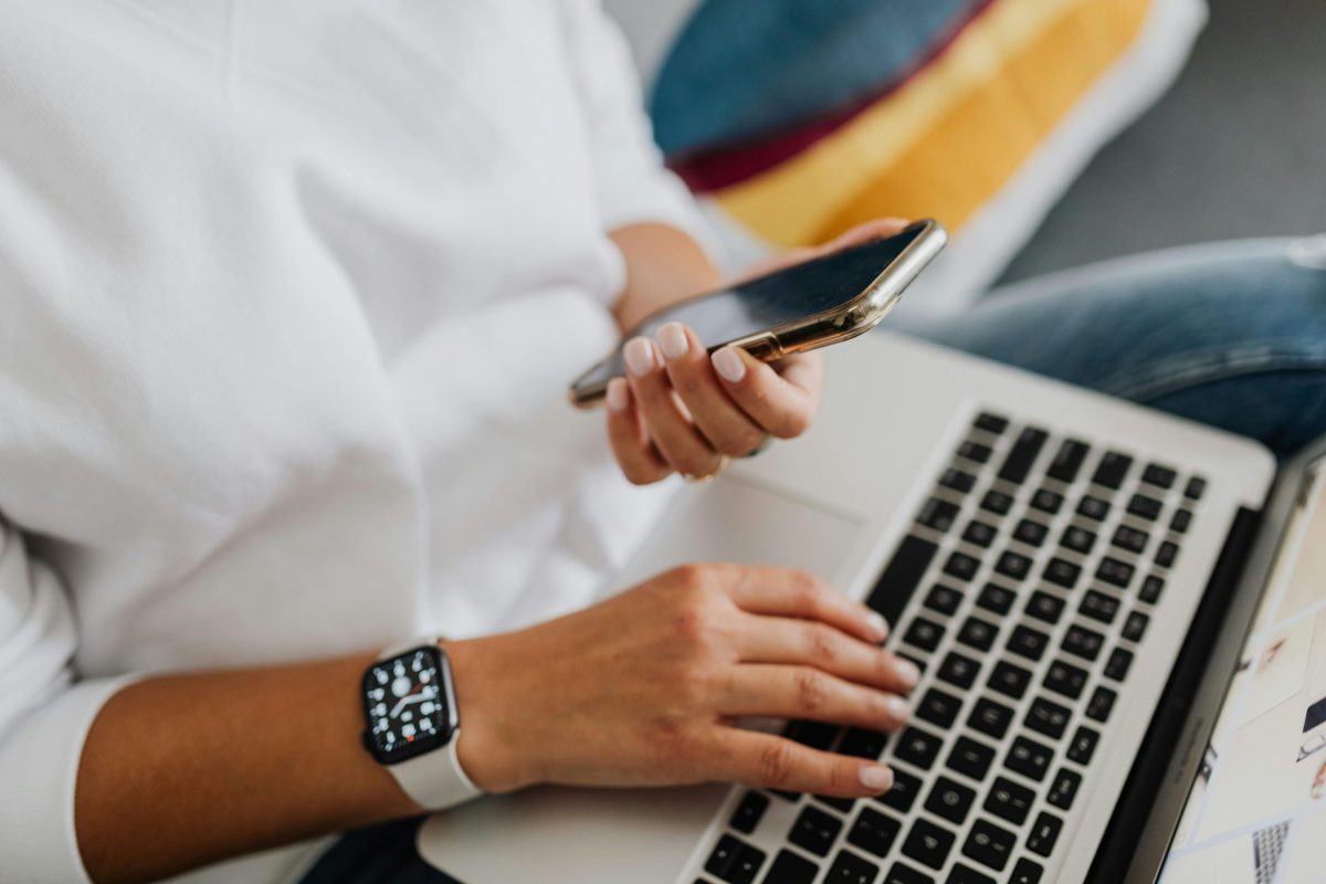 jakob-owens-WUmb_eBrpjs-unsplash A person using a laptop while holding a smartphone.